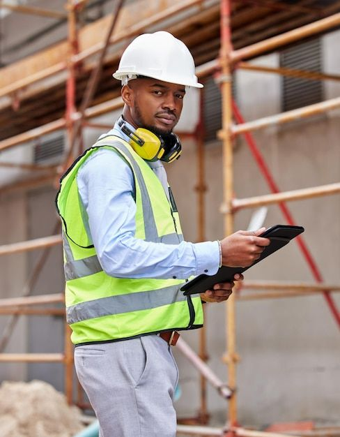 A business owner in safety gear reviewing operations on a tablet at a work site